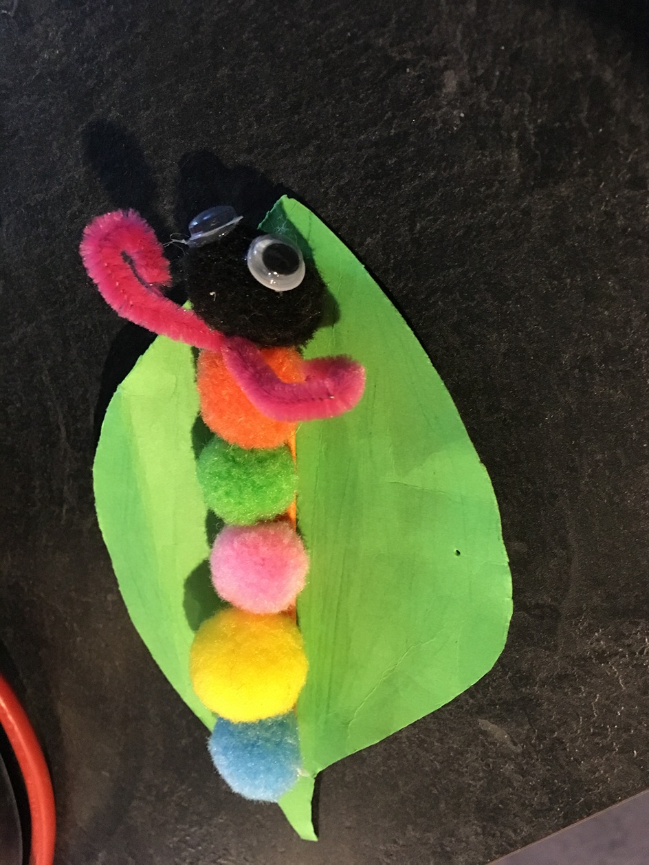 Children's craft: A paper leaf with a pom pom caterpillar
