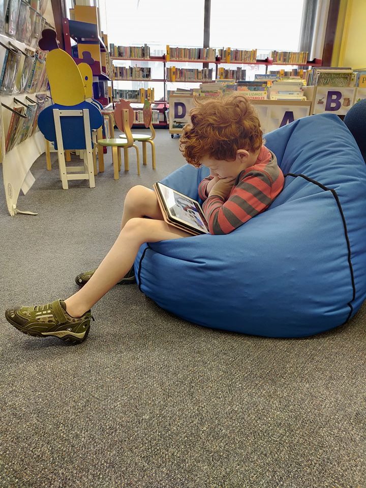 Boy sitting on a beanbag reading on an iPad