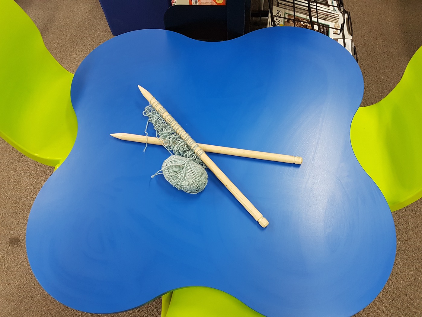 Knitting needles and yarn on a bright blue table